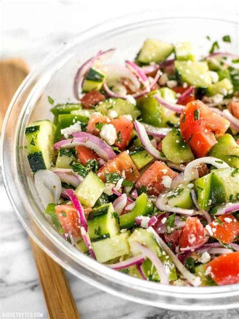 a glass bowl filled with cucumber, onion and tomato salad on top of a ...