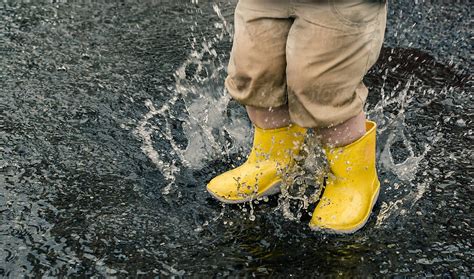 Yellow Boots Splash In A Rain Puddle by Leslie Taylor - Stocksy United