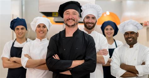 Proud team of chef, sous chefs and cooking assistants looking at camera ...