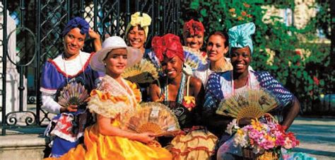 a group of women dressed in colorful costumes posing for a photo with fans and flowers