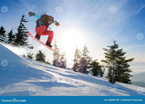 Snowboarder Jumping on the Red Snowboard in Mountains at Sunny Day. Snowboarding and Winter ...