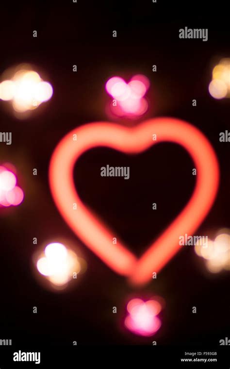 Neon love heart shape sign at night on black background with mini love ...