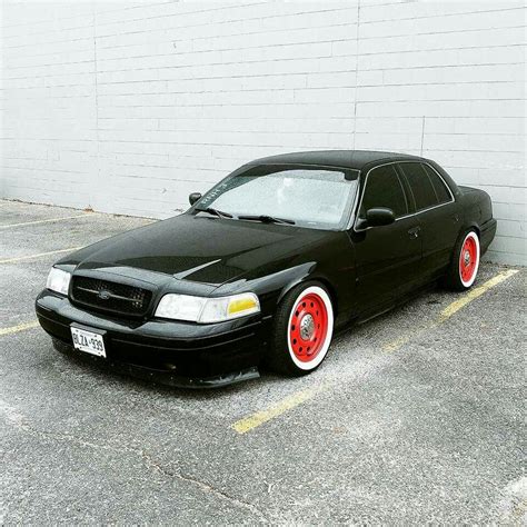 Black Car with Red Rims Parked Next to White Brick Wall