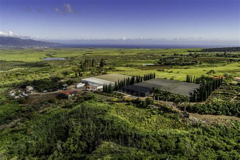 an aerial view of a large building surrounded by lush green fields and trees with mountains in ...