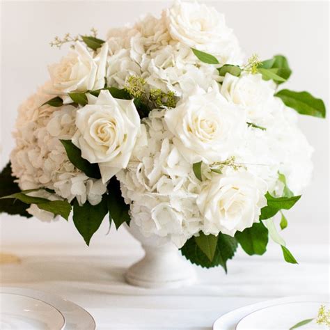 a bouquet of white flowers sitting on top of a table next to plates and cups