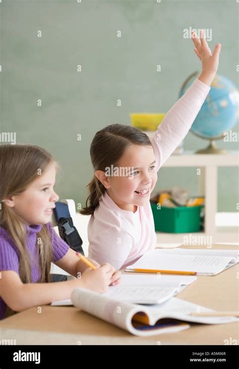 Girl raising hand in classroom Stock Photo - Alamy