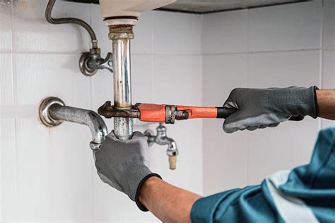 Premium Photo | Plumber using a wrench to repair water pipe under the sink.