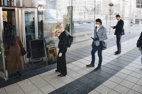 People standing in line outside cafe keeping distance stock photo