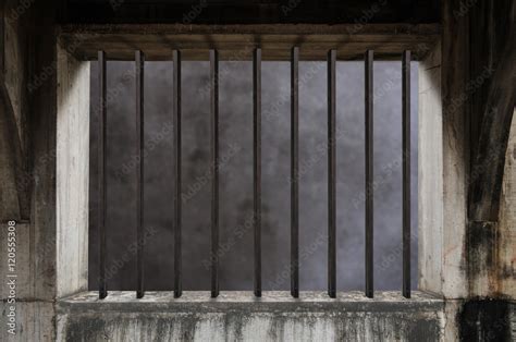 Interior of a prison cell with light shining through a barred window ...