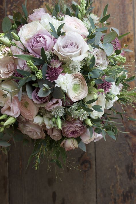 a bridal bouquet with pink and white flowers on a wooden table next to wood planks