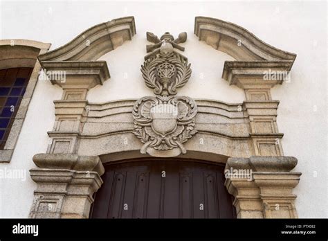 Detail of the lateral portal with a broken pediment and religious coat ...