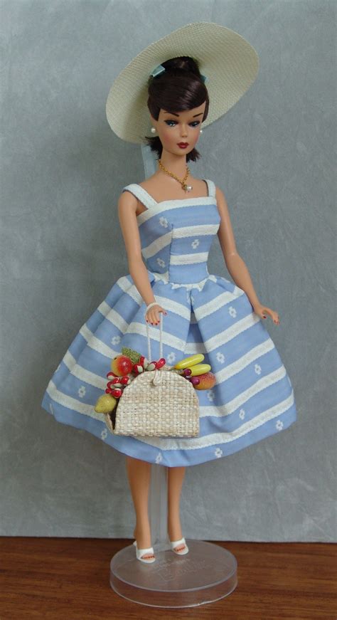 a doll wearing a blue and white dress holding a straw hat