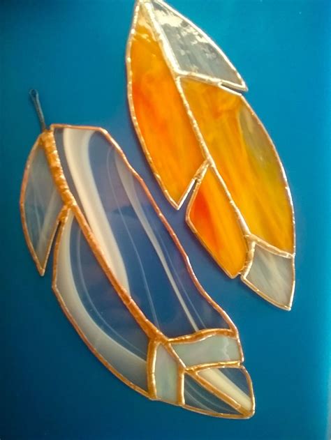 two stained glass pieces sitting on top of a blue surface