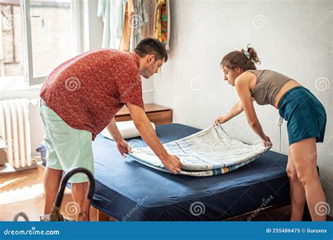 Cheerful Millennial Couple Making Bedsheet Together Stock Image - Image ...