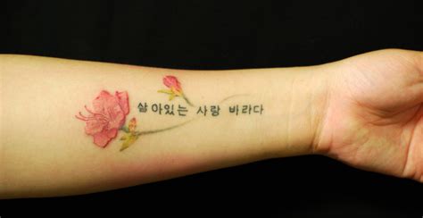 a woman's arm with a flower and the words in korean on her left wrist