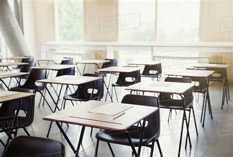 Tests on desks in empty classroom - Stock Photo - Dissolve