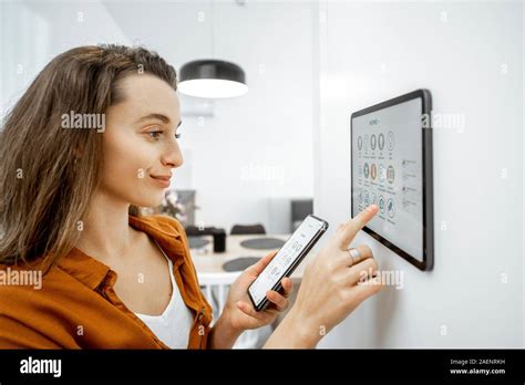 Young woman controlling home with a digital touch screen panel ...