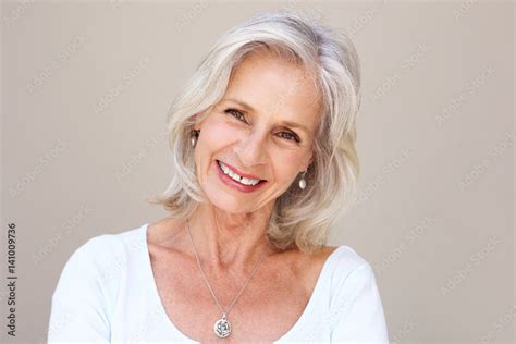 beautiful older woman smiling and standing by wall Stock-Foto | Adobe Stock