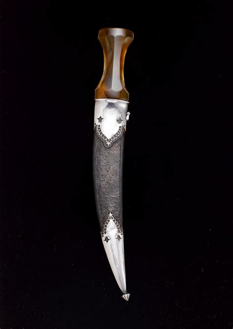 a silver and brown vase sitting on top of a black table