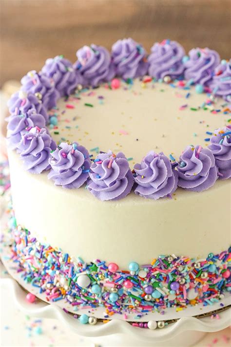 a white cake with purple frosting and sprinkles