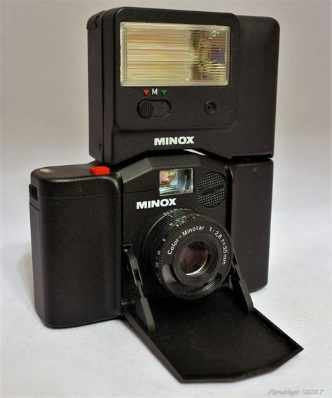 an old minox camera sitting on top of a black case with a flash drive attached to it