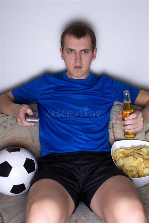 Bored Man in Football Uniform Sitting in Living Room and Watching Tv with Beer and Chips Stock ...