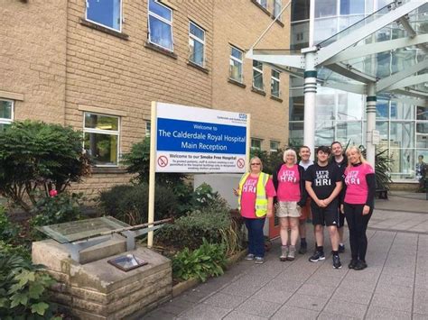 some people are standing in front of a building and posing for a photo with the sign