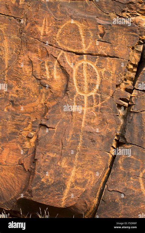 Ancient aboriginal rock art engravings, symbols of initiation rites, on red stone walls in ...