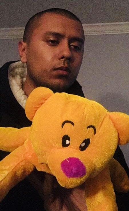 a man is holding a large yellow teddy bear with pink nose and eyes on his chest