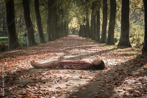 Teenage girl in dress lying on path in forest Stock Photo | Adobe Stock