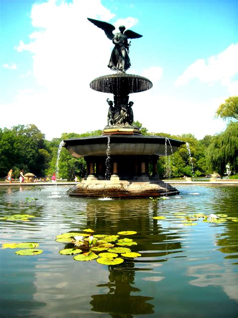 a fountain with a statue in the middle surrounded by lily pads