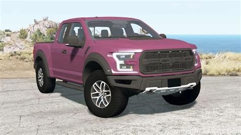 a pink truck parked on top of a parking lot next to the ocean and grass