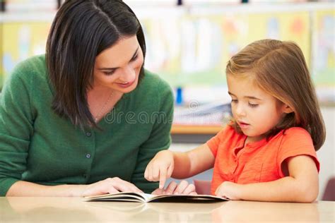 Elementary Pupil Reading with Teacher in Classroom Stock Image - Image ...