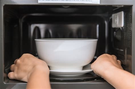 Premium Photo | People putting food ceramic bowl in to the microwave for reheating food.