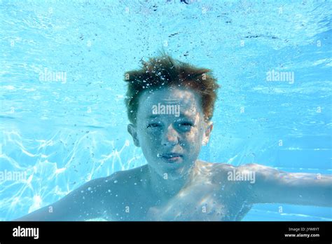 Auburn haired teenage boy, underwater in a swimming pool, looking into camera Stock Photo - Alamy