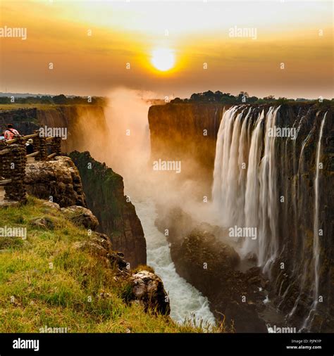 Victoria falls sunset with orange sun and tourists Stock Photo - Alamy