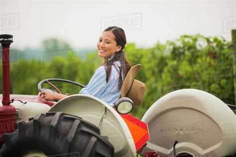 Asian woman driving tractor in field - Stock Photo - Dissolve