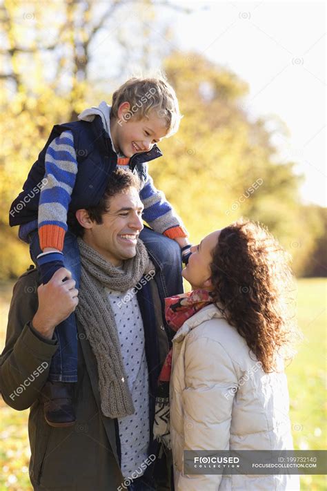 Happy family smiling together in park — outdoors, Carrying - Stock Photo | #199732140