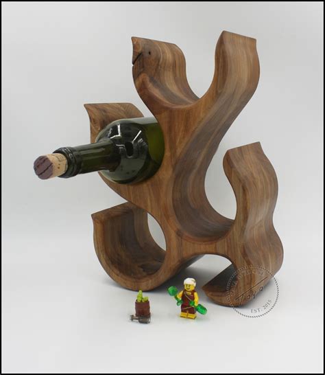 a wine bottle holder made out of wood with two figurines next to it