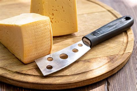 Two pieces of cheese and a cheese knife on a wooden kitchen board - Creative Commons Bilder