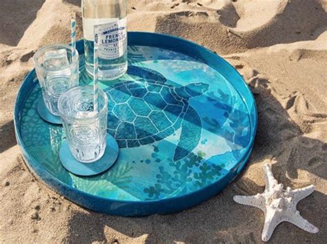 there are glasses and bottles sitting on the tray in the sand with starfish nearby