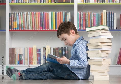 Cute boy reading book in library Stock Photo | Adobe Stock