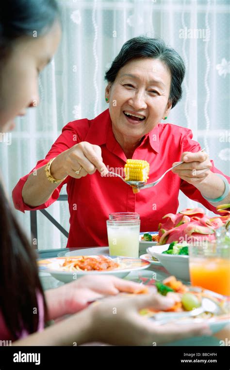 Grandmother and granddaughter at dining table, eating Stock Photo - Alamy