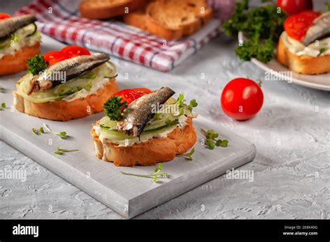 Smoked sprat sandwich - fish, fresh cucumber and tomato. Sprat sandwiches on toasted slices of ...