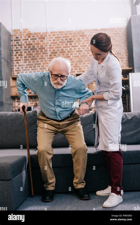 Doctor assisting male patient with cane Stock Photo - Alamy