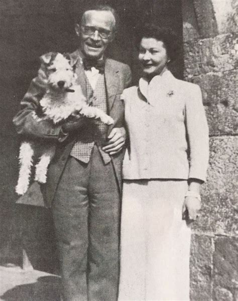 an old black and white photo of a man and woman holding a small dog while standing next to each ...