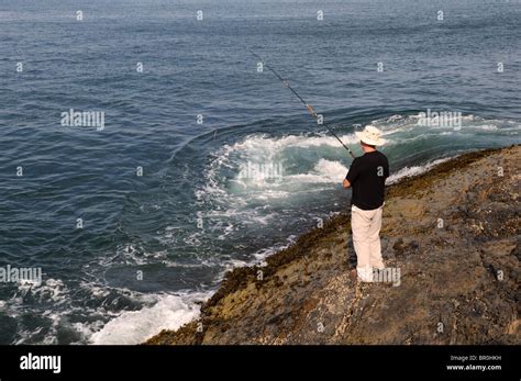 Man fishing off rocks near Mwnt Cardigan Bay Coastal Path Ceredigion ...