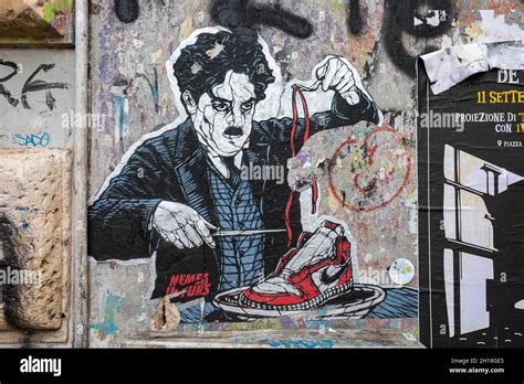 Cut-to-shape street art poster of Charlie Chaplin eating Nike sneaker. Trastevere district of ...