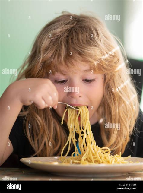 Tasty food, messy child eating spaghetti. Young kid sitting on the ...