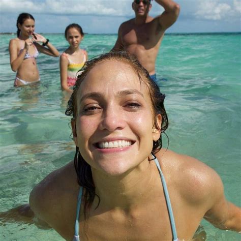 a group of people standing in the ocean with one woman wearing a bathing suit and smiling at the ...
